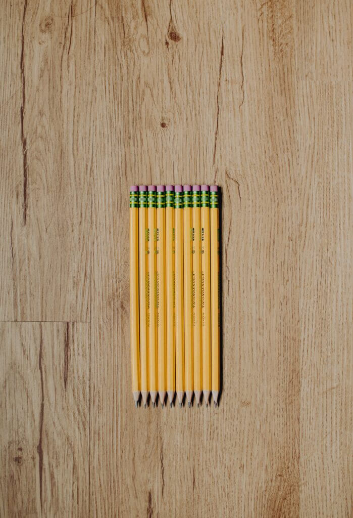 a neat row of sharpened pencils on a wooden surface.